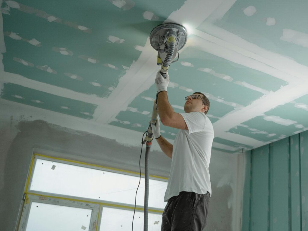 A professional worker sanding the ceiling during a home renovation project. Indoor construction setting.